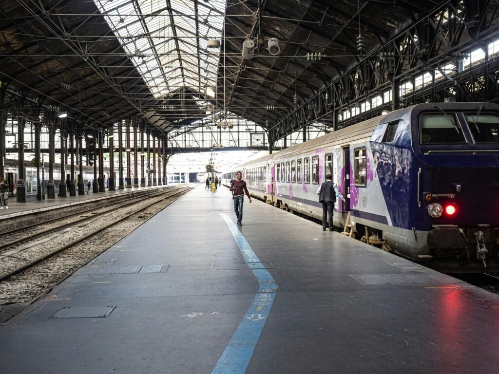 Interior view of a Paris train station showing a train and passengers on the platform.